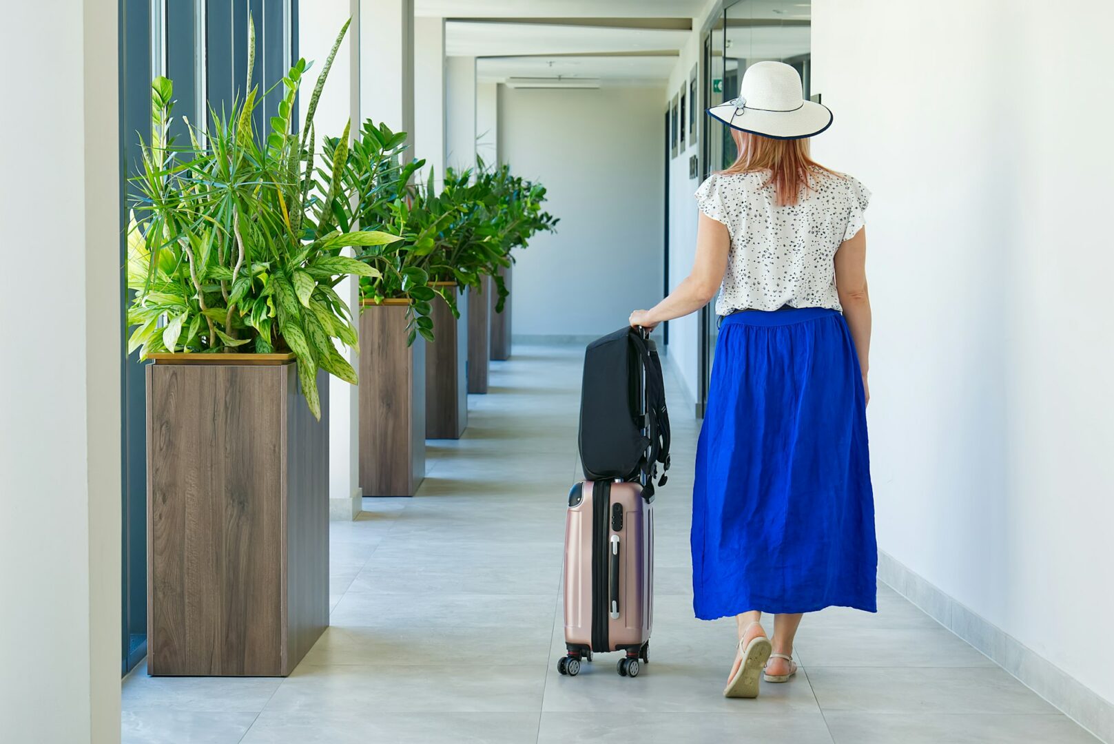 girl tourist checks out of the hotel. Tourist with a suitcase walks along the corridor in the hotel